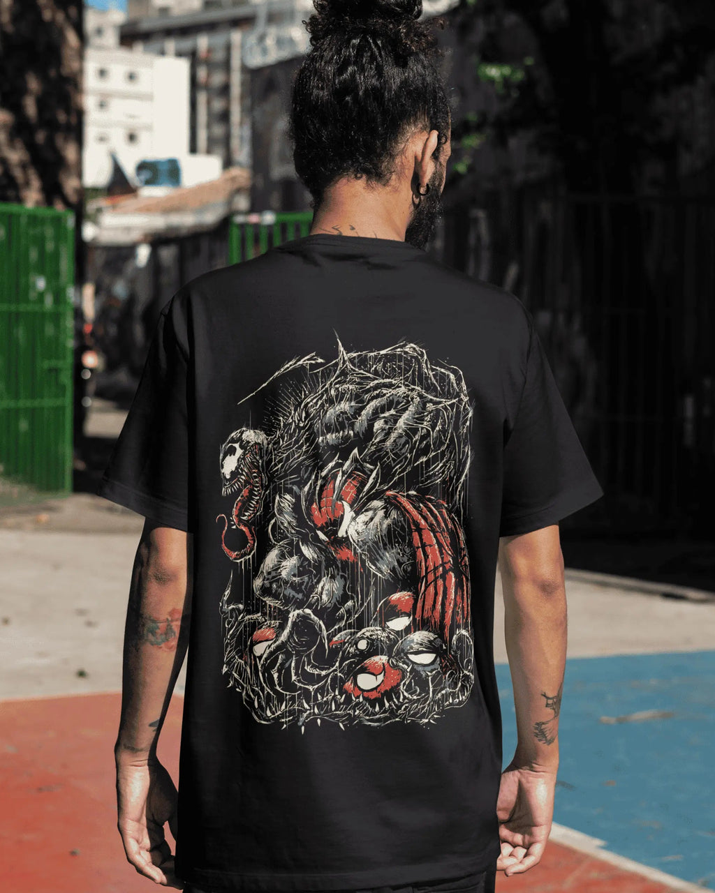 Person wearing a black t-shirt with a graphic design, standing on an urban street.