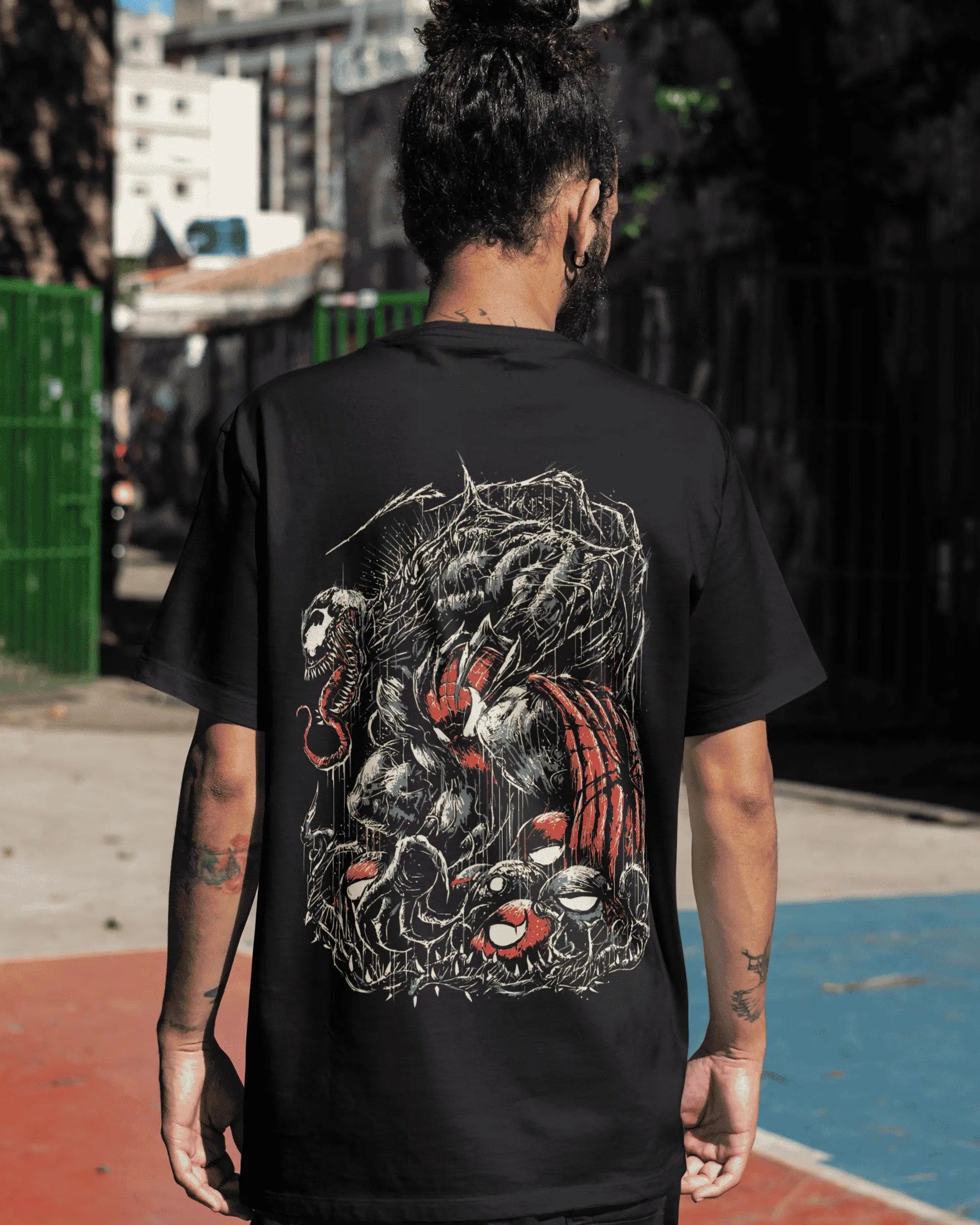 Person wearing a black t-shirt with a graphic design, standing on an urban street.
